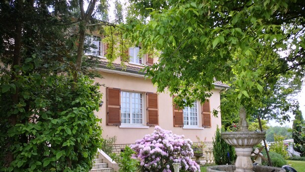 Una casa con jardín, una fuente y una escalera que lleva a la entrada.