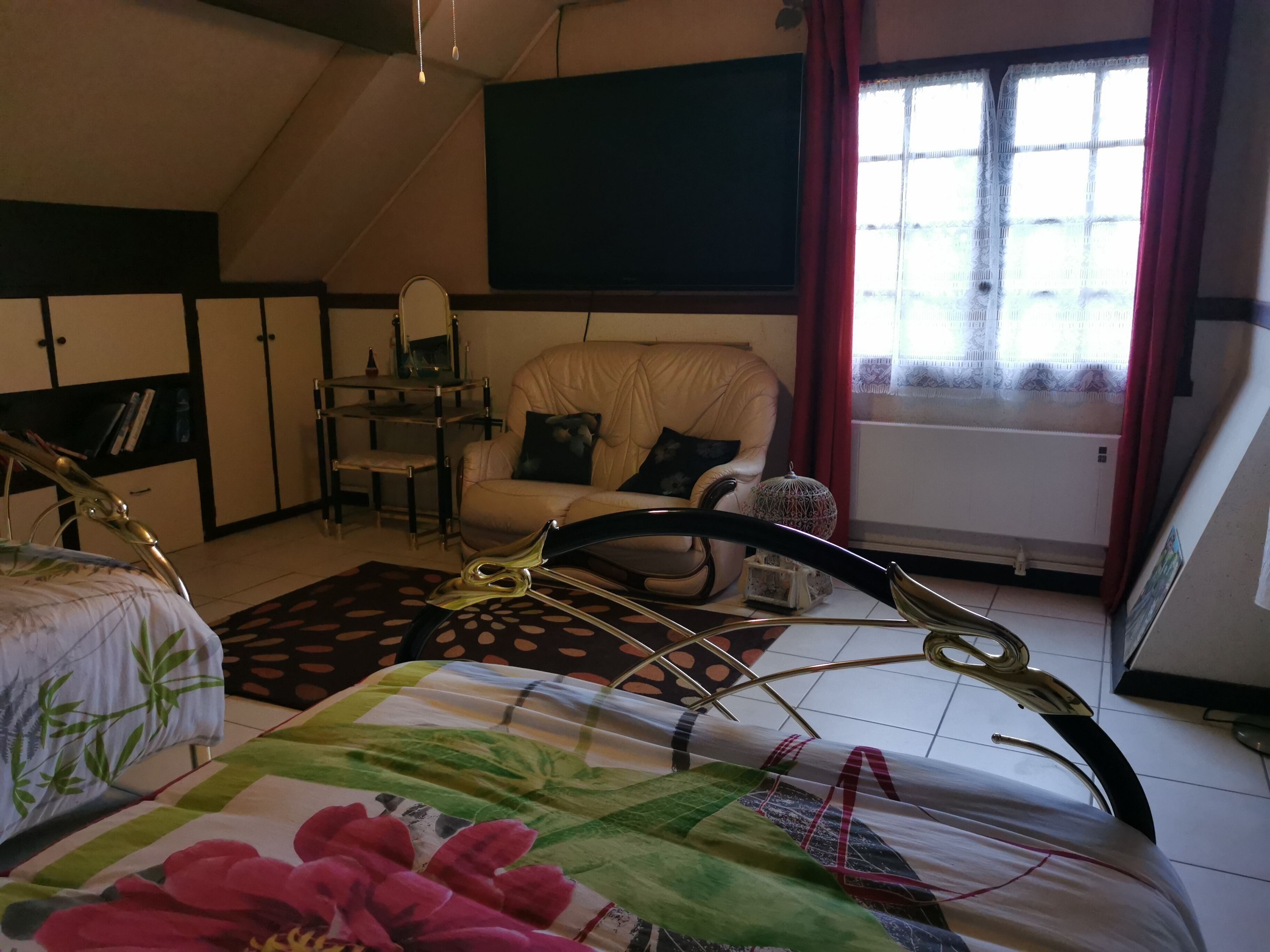 Una camera da letto con un letto, una sedia, una scrivania e una finestra con tende.