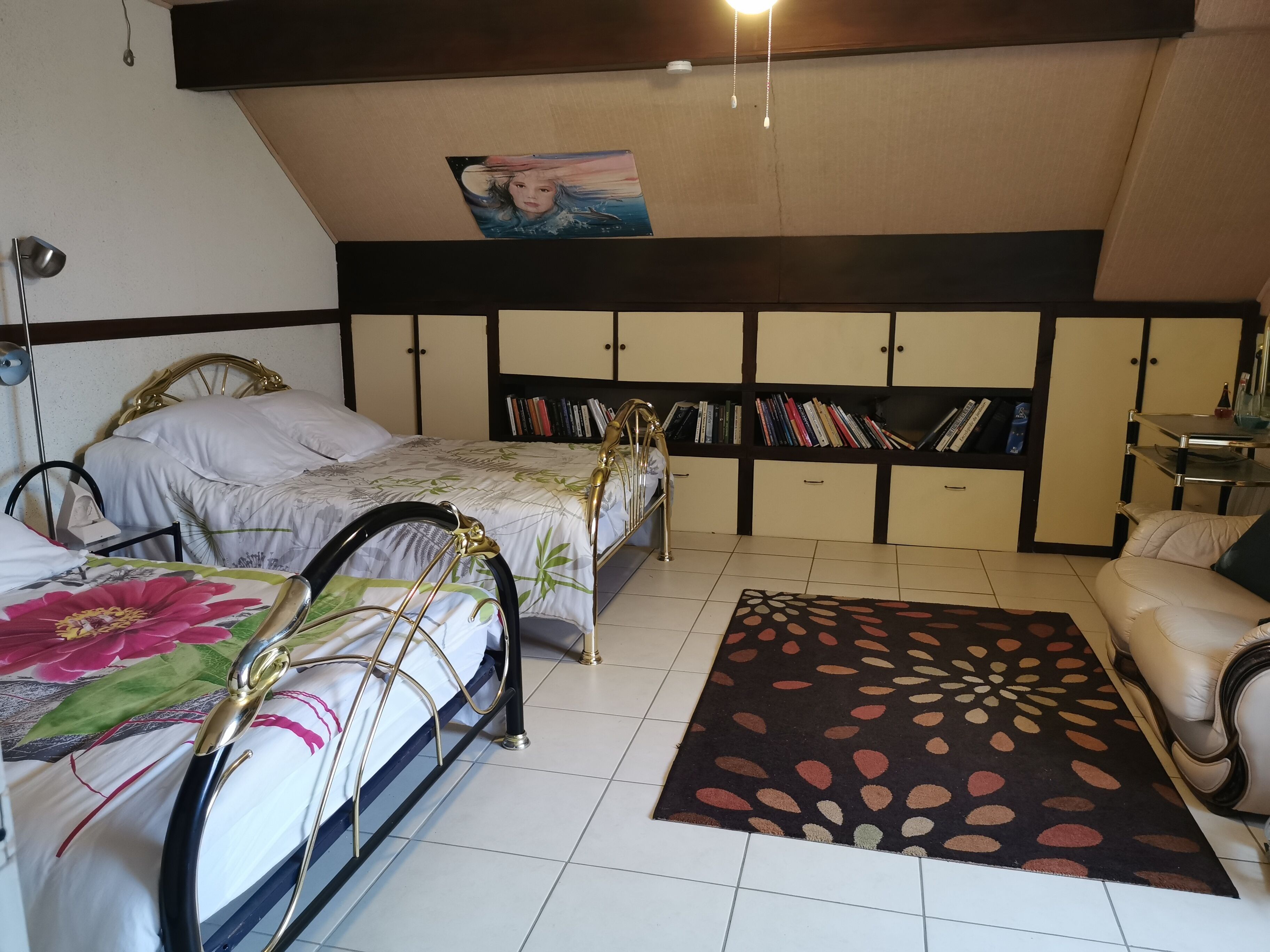 Un dormitorio con dos camas, una estantería, un escritorio y una silla.