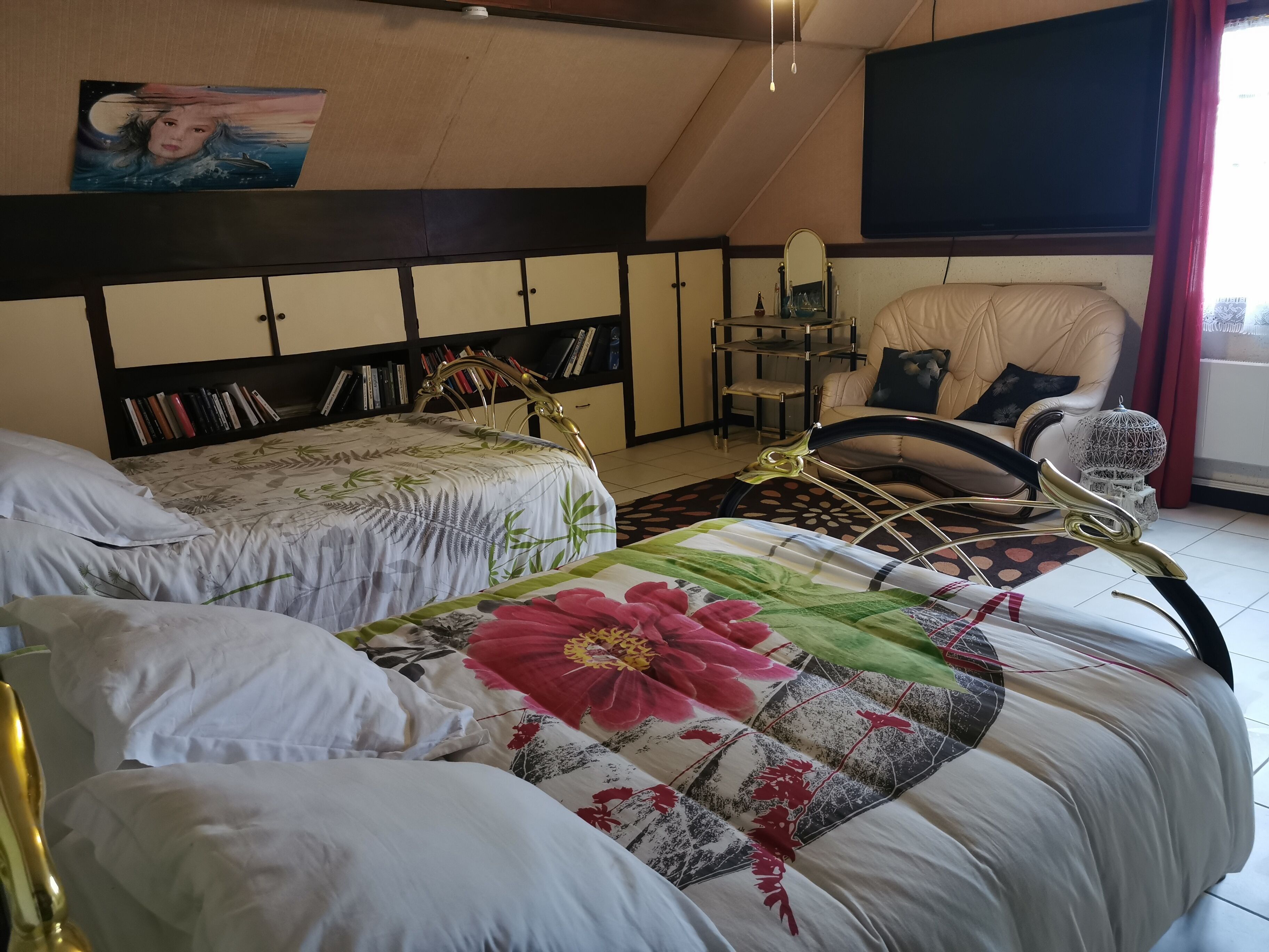 A bedroom with two beds, a bookshelf, a chair, and a TV.