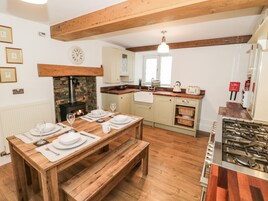 Una cucina accogliente con un tavolo di legno apparecchiato per mangiare, un piano cottura integrato e un camino in mattoni.