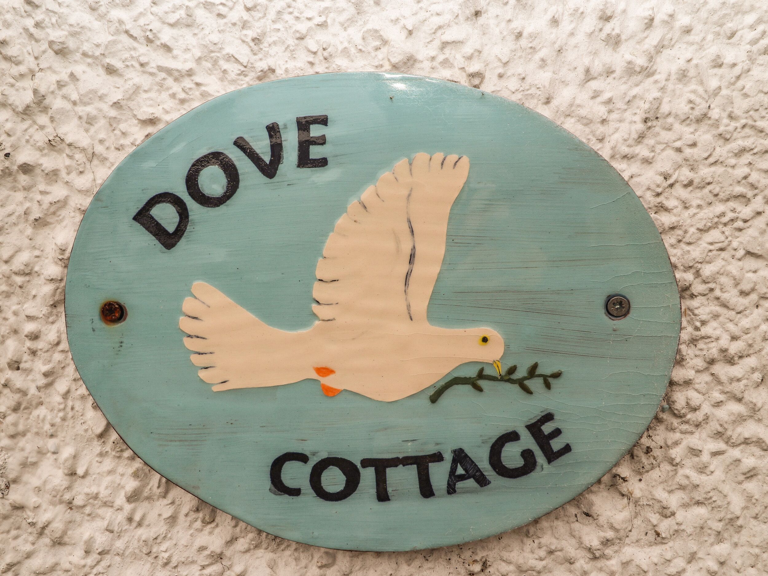 Een rond bord met een duif en de tekst 'DOVE COTTAGE'.
