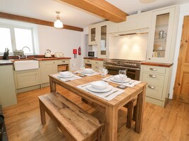 Una cucina moderna con pavimento in legno, un tavolo da pranzo imbandito per sei persone ed elettrodomestici a incasso.