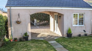 A small, single-story building with a sloped roof, a gravel driveway, and a pathway leading to a door. - Cranny Corner (Ballymena)