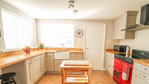 A kitchen with wooden countertops, a sink, a stove, and a clock on the wall. - Cranny Corner (Ballymena)