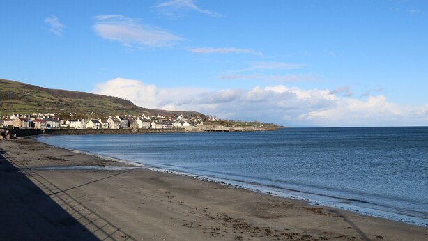 A coastal town with a sandy beach and a row of houses along the shore. - Cranny Corner (Ballymena)