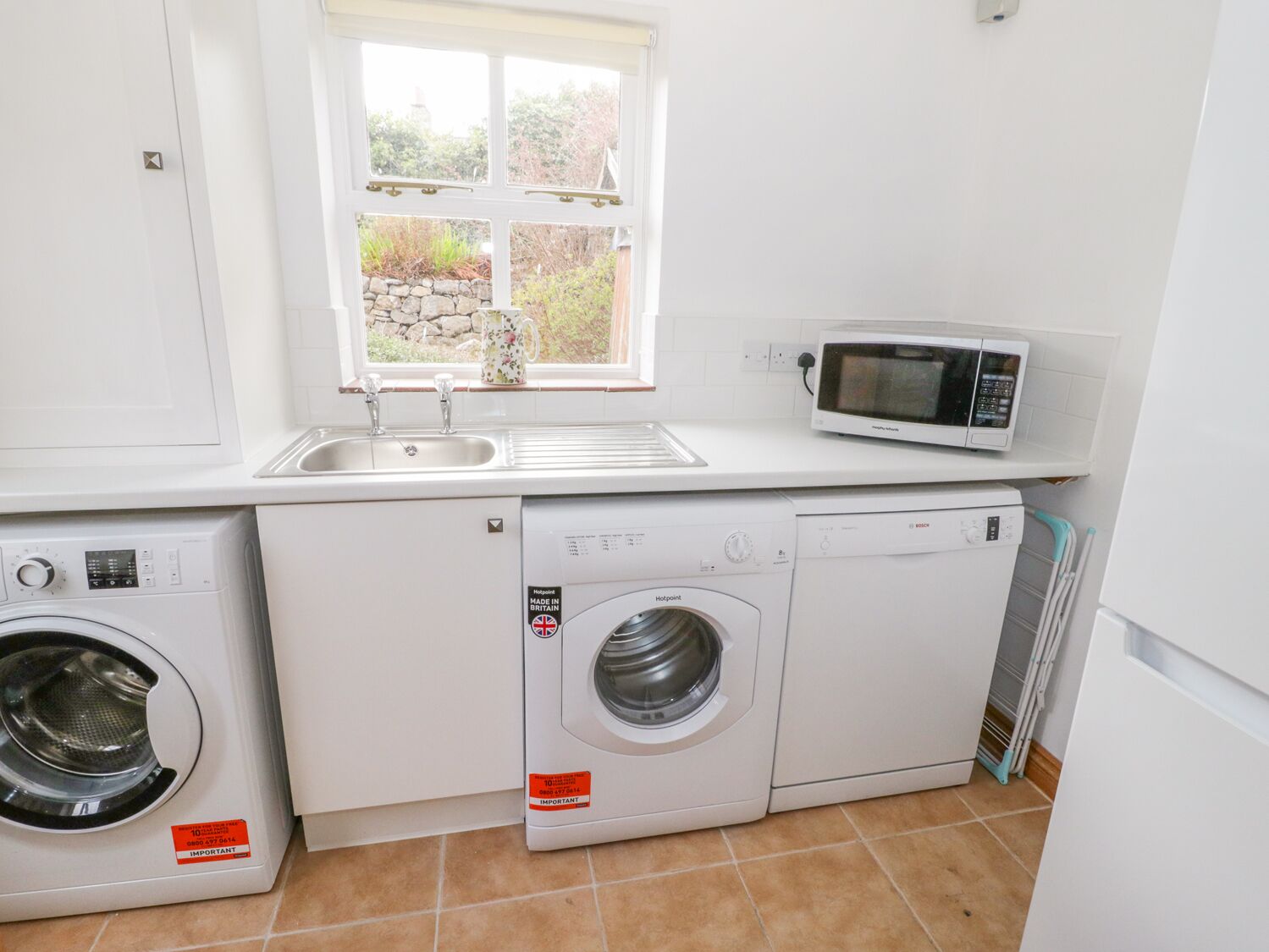 Una cocina compacta equipada con lavadora, microondas y lavabo.