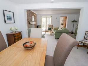 Relax in this inviting living space with a green sofa, dining table, and comfortable seating for a cozy atmosphere.