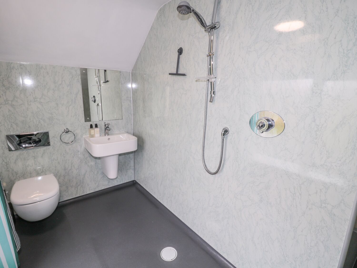 Ein modernes Badezimmer mit Waschbecken, Toilette und Dusche inklusive Handbrause.