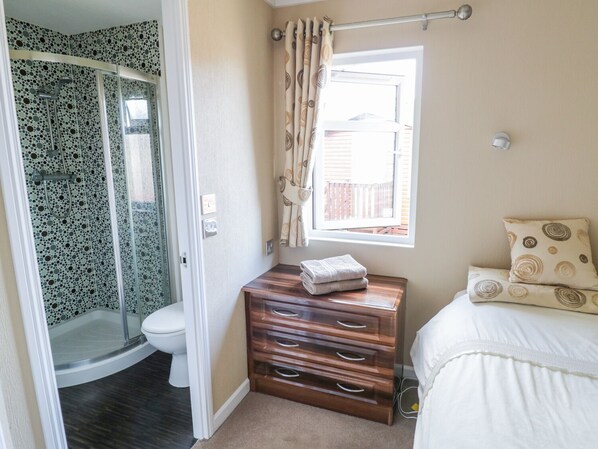 Un baño con ducha, inodoro y ventana con cortinas.