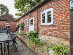 Une maison en briques avec un patio, un espace salon extérieur et un mur en pierre.