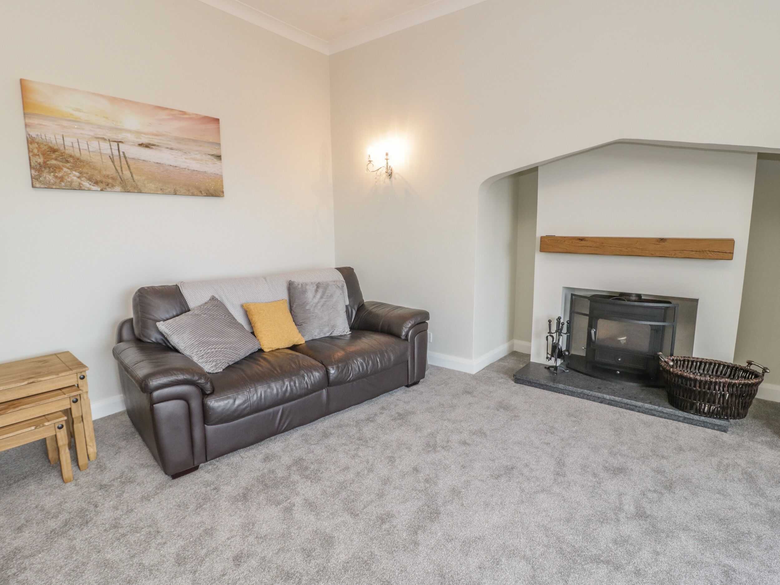 A living room with a leather sofa, a painting on the wall, a fireplace, and a small wooden table.