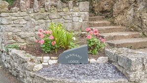 A stone wall with a sign reading "SANNANS LODGE". - Sannans Lodge (Llandudno)