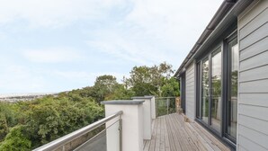 A wooden deck with a glass balustrade, overlooking a lush green landscape. - Sannans Lodge (Llandudno)