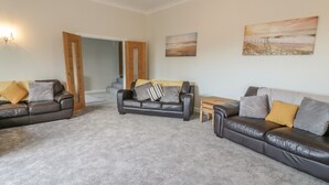 A living room with three leather sofas, a coffee table, and a staircase leading to another room. - Sannans Lodge (Llandudno)