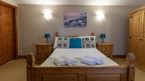 Een slaapkamer met een houten bed, twee nachtkastjes, een wandlamp en een schilderij boven het bed.