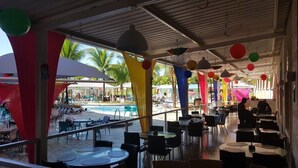 Un espace extérieur aménagé pour les repas, avec des tables et des chaises, une piscine et des parasols.