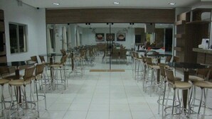 Un vaste espace dédié à la salle à manger, avec de grandes tables et des chaises, un sol carrelé et un aménagement intérieur moderne.