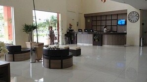 Un hall d’entrée spacieux avec un comptoir d’accueil, des coins salon et une grande plante.