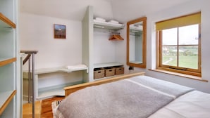 A bedroom with a bed, a wardrobe, a mirror, and a window with a view. - The Folly (Hereford)