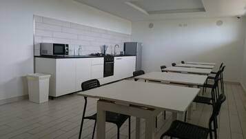 A modern kitchen with white cabinets, a microwave, and a stove. There are six black chairs around a white table.