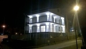 Un edificio de varios pisos con balcones y ventanas iluminadas en la noche.