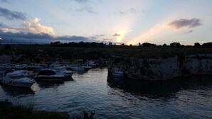 Un puerto deportivo con barcos amarrados durante la marea baja, rodeado de terreno rocoso y vegetación escasa.