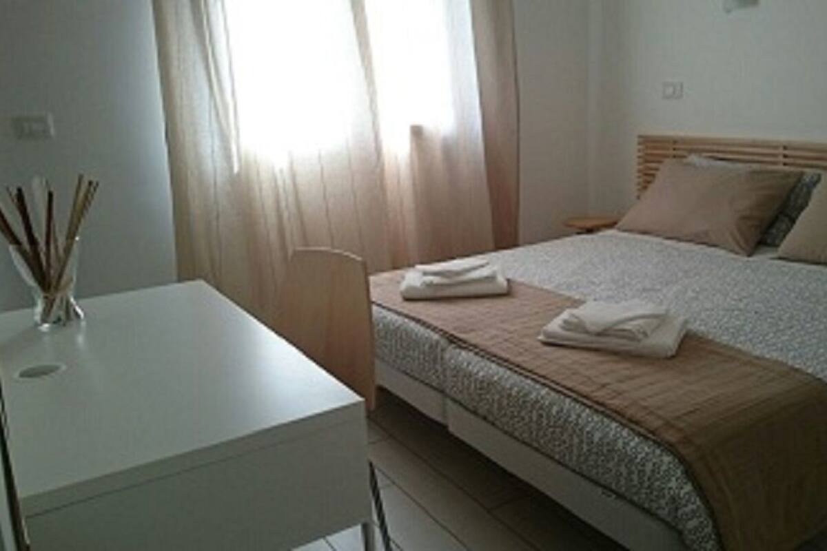 Una habitación de hotel con una cama, una mesita de noche y un escritorio.