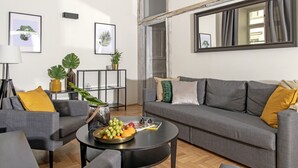 A modern living room with a grey sofa, a coffee table with fruit, and a large mirror. - 3D FLORIANSKA 15 Apartament (Kraków)