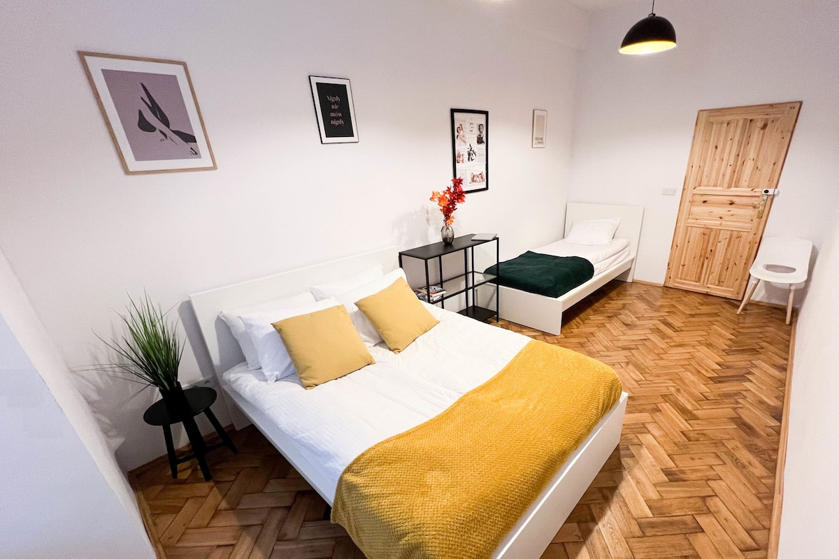 A bedroom with a bed, bedside table, and a small stool.