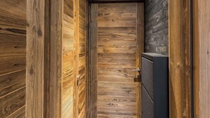 A narrow hallway with wooden walls and a black door. - Steps from Megève Rink & Chamois Gondolas (Megève)