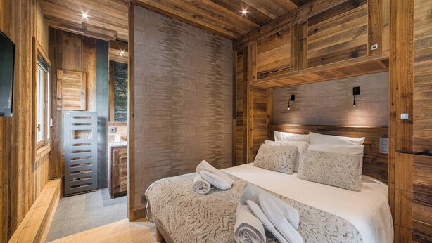 A wooden cabin-style bedroom with a bed, pillows, and a nightstand. - Steps from Megève Rink & Chamois Gondolas (Megève)