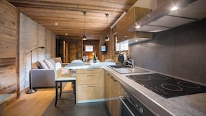 A modern kitchen with wooden accents, a dining area with a sofa, and a bar area. - Steps from Megève Rink & Chamois Gondolas (Megève)