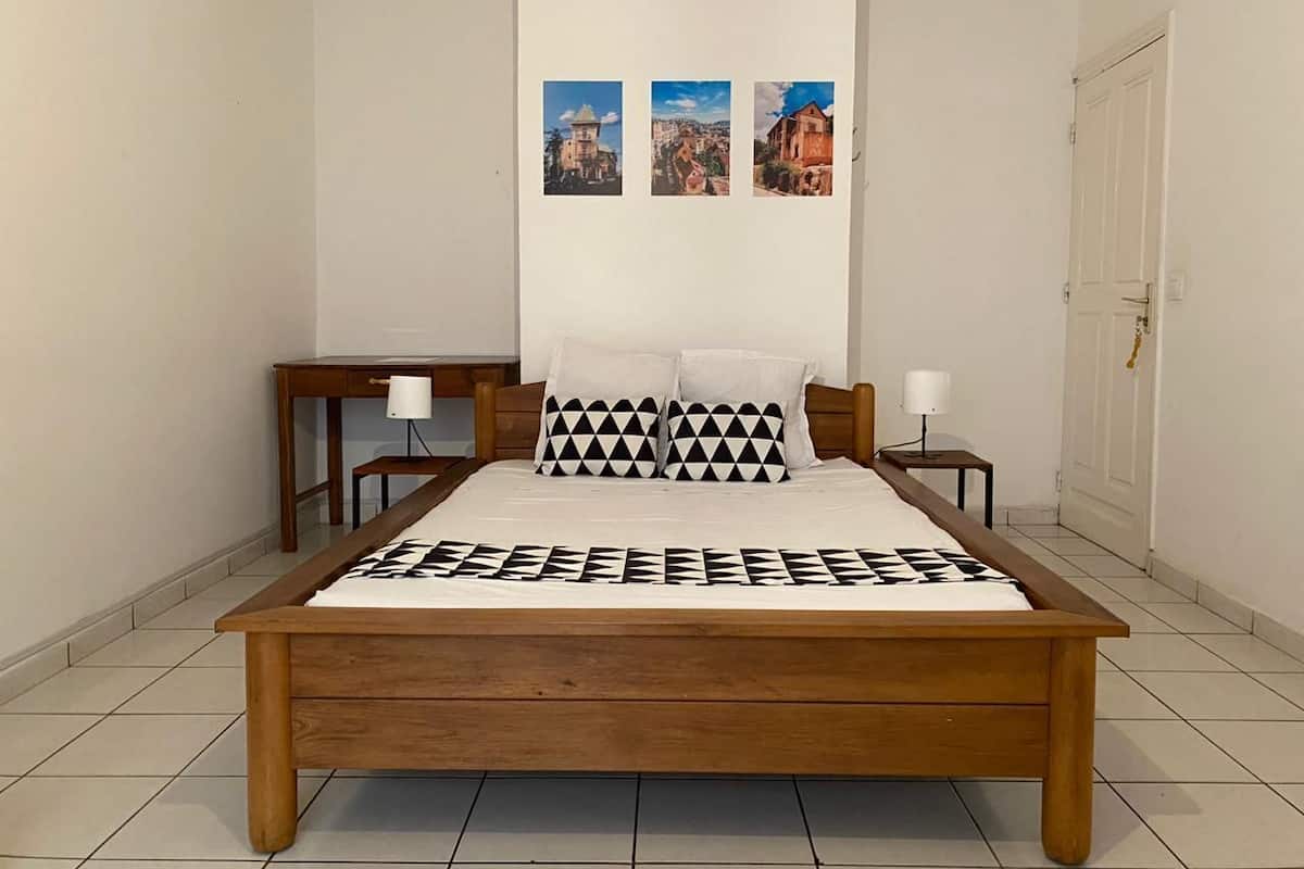 A bedroom with a wooden bed, two bedside tables with lamps, and three framed pictures on the wall.