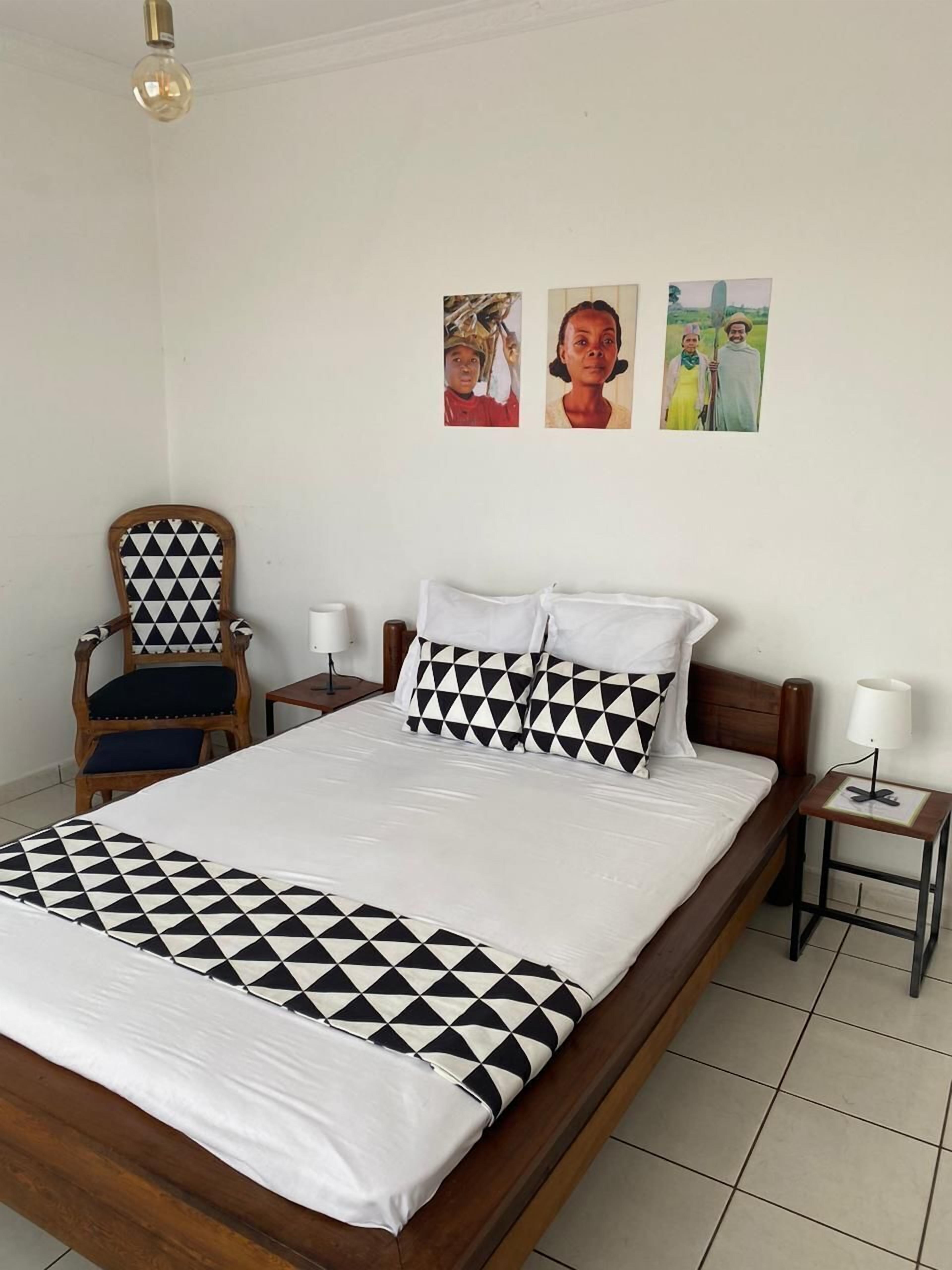 Una cama bien hecha con una colcha a cuadros, un cabecero de madera y dos mesitas de noche con lámparas.