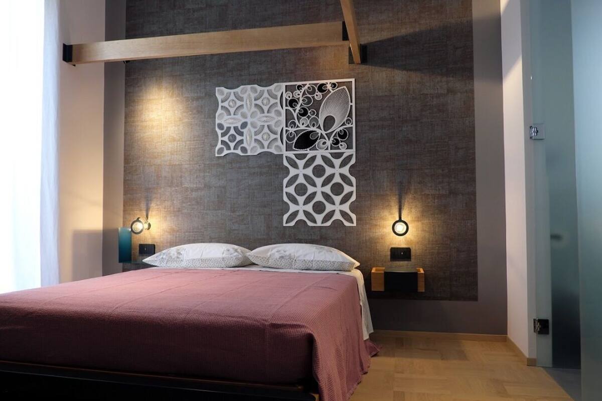 A modern bedroom with a large bed, two bedside tables, and a decorative wall panel.