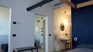 A modern bedroom with a bed, bedside table, and a bathroom with a sink and mirror. - InVento bnb (Civitanova Marche)