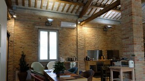 A rustic kitchen with exposed brick walls, wooden beams, and a large window. - InVento bnb (Civitanova Marche)