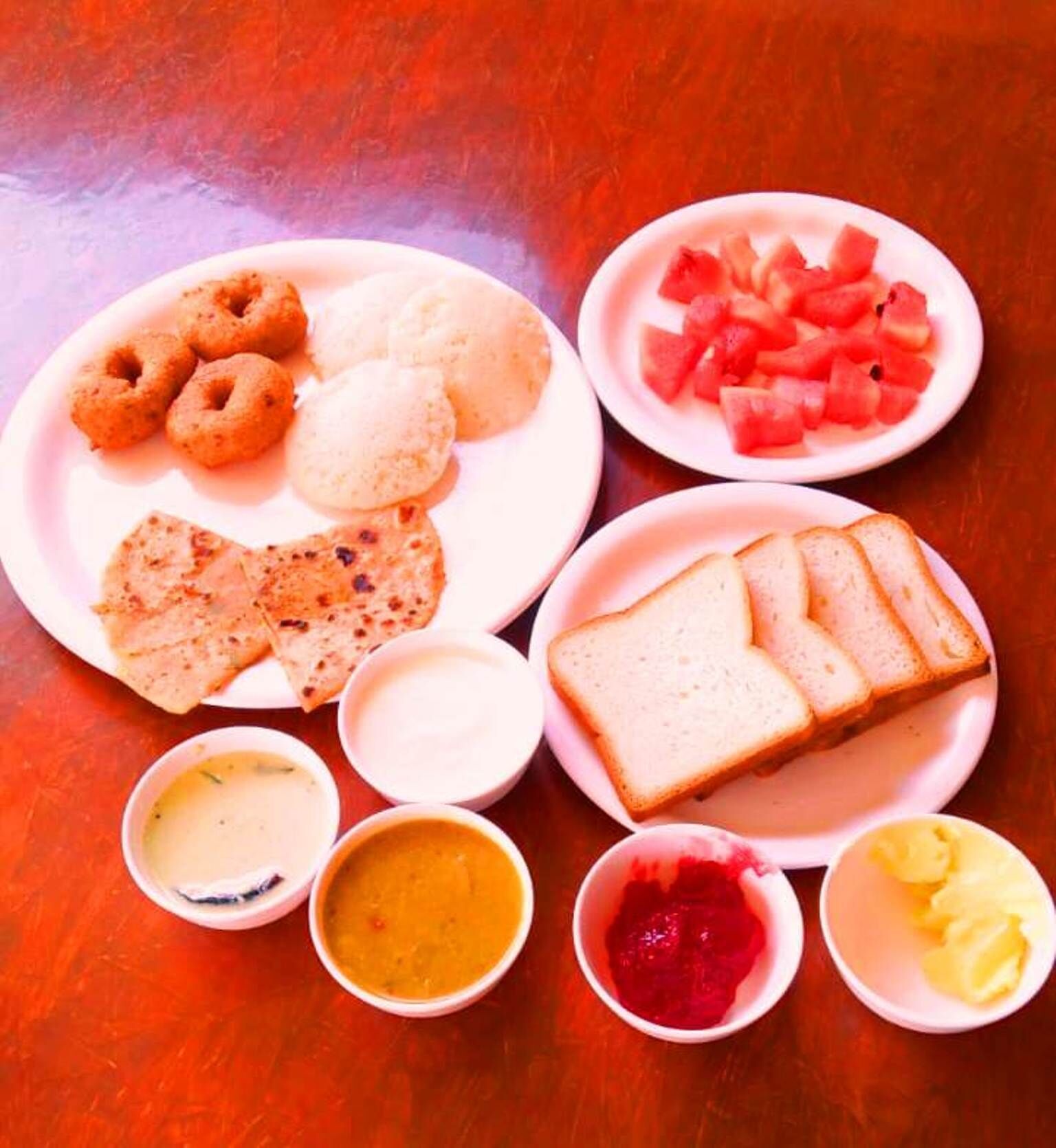 A table with various food items including flatbreads, bread, and a plate of sliced bread.