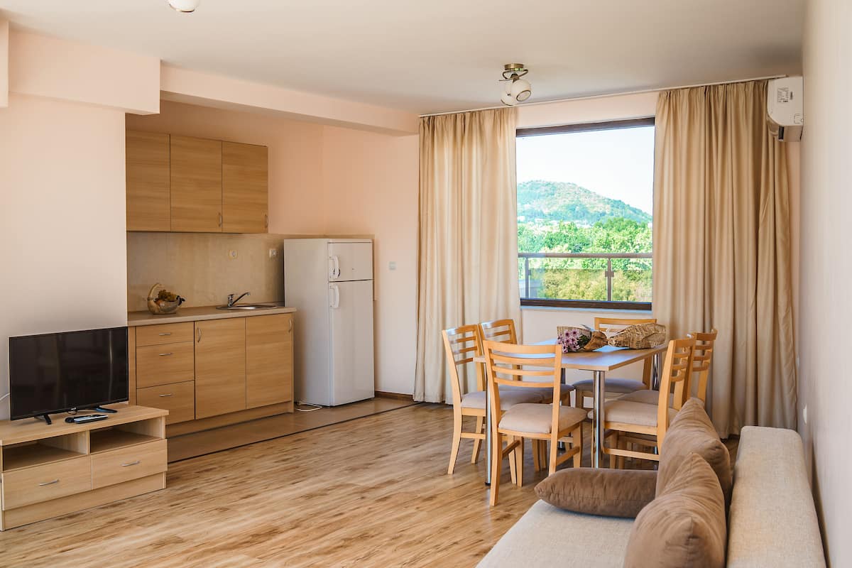 Ein kompakter Wohnraum mit Küchenzeile, einem Essbereich mit Holzmöbeln und einer Couch.