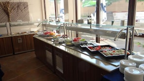 A buffet counter with various food items and a glass display case.