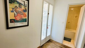 A hallway with wooden flooring, a framed artwork, and a door leading to a bathroom. - La Maison Blanche: private heated pool, 7 bedrooms (Sarlat-la-Canéda)