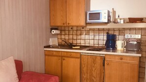 Eine kleine Küche mit Holzausstattung, einer Mikrowelle, einer Kaffeemaschine und einem Toaster.