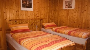 Ein Zimmer mit Holzboden und zwei Betten, jeweils mit gestreifter Bettwäsche.