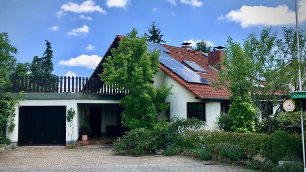 Ein Haus mit Solaranlage auf dem Dach, einer Garage und einem gepflegten Garten.