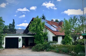 Una casa con paneles solares en el techo, un garaje y un jardín bien cuidado.