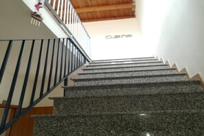 A staircase with granite steps and black railings, leading to a room with a wooden ceiling and a visible 'Osne' sign.