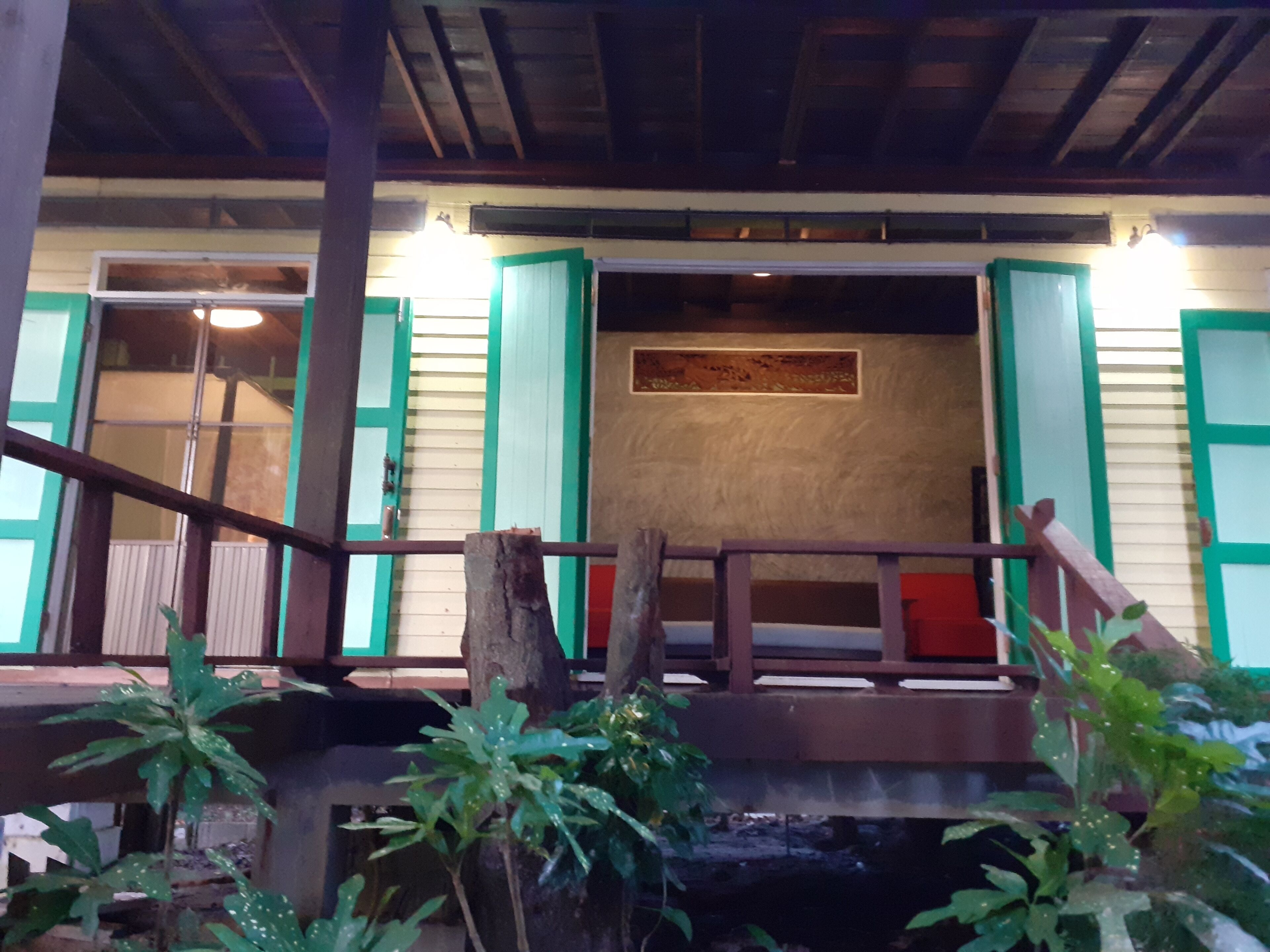 A wooden staircase leading to a room with green shutters and a small balcony.