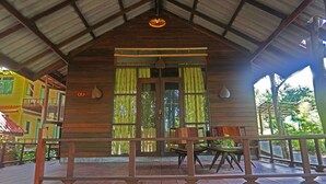 A wooden cabin with a porch, large windows, and a hanging light fixture. - Baan Klong Kleng (Ranong)