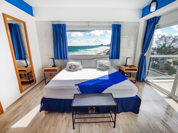 Una camera da letto con un letto grande, un comodino, una finestra vista mare e uno specchio.